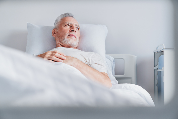 Mature caucasian male patient resting while lying on bed after cataract surgery.