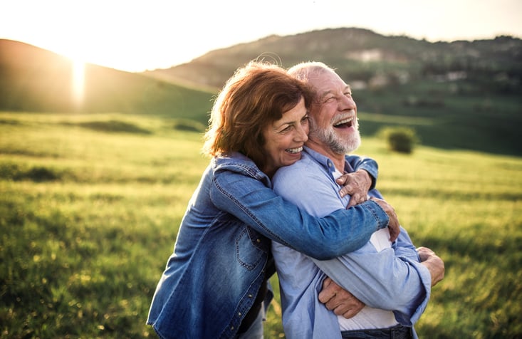 Refractive Lens Exchange_Smiling older couple embracing in a sunlit field
