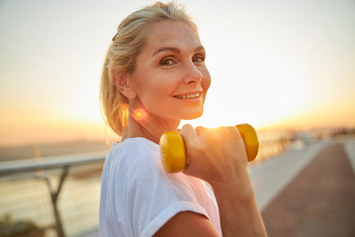 A woman happy on the beach after eyelid surgery.