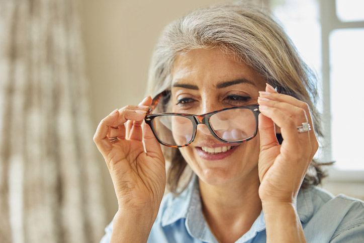 Woman adjusting her glasses during a routine eye exam, checking vision clarity and prescription accuracy.