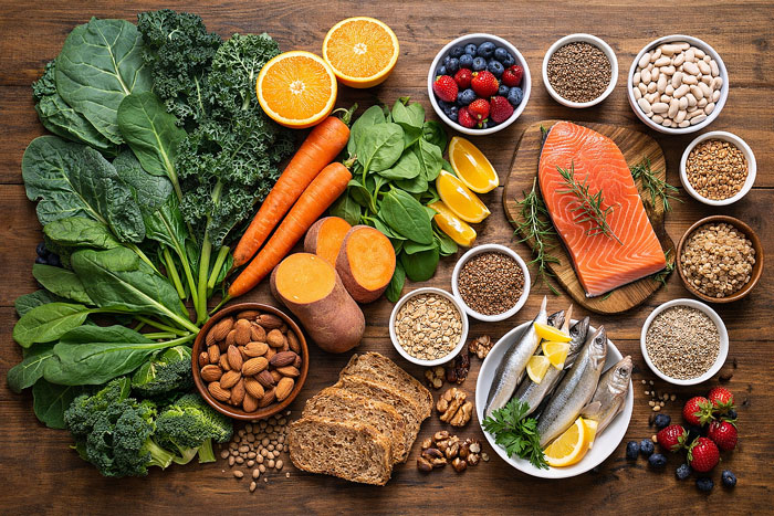what to eat for eye health shown as leafy greens colorful fruits vegetables salmon sardines nuts seeds beans and whole grains on a wooden table for Vantage Eye Center patients