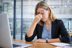 Business woman is expieriencing digital eye strain which contributes to blurry vision causes, with Vantage Eye Center.