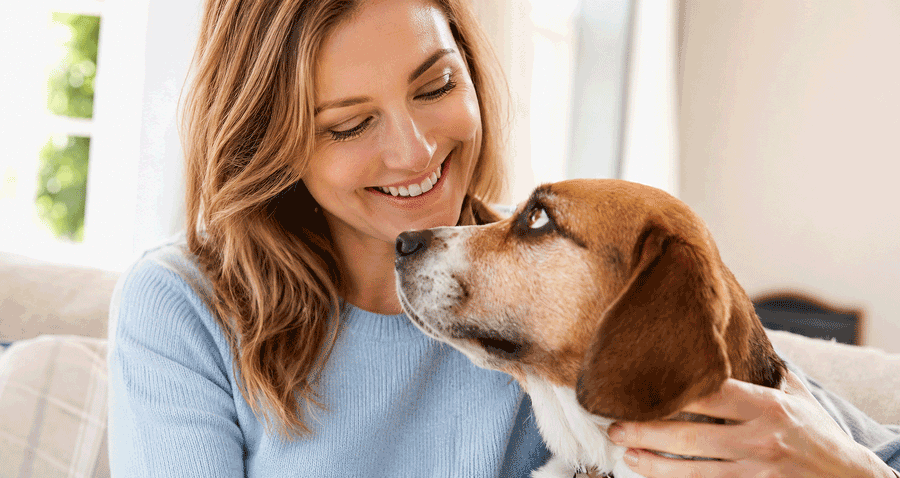 Woman cuddling her dog at home, representing eye allergy treatment for pet owners at Vantage Eye Center.